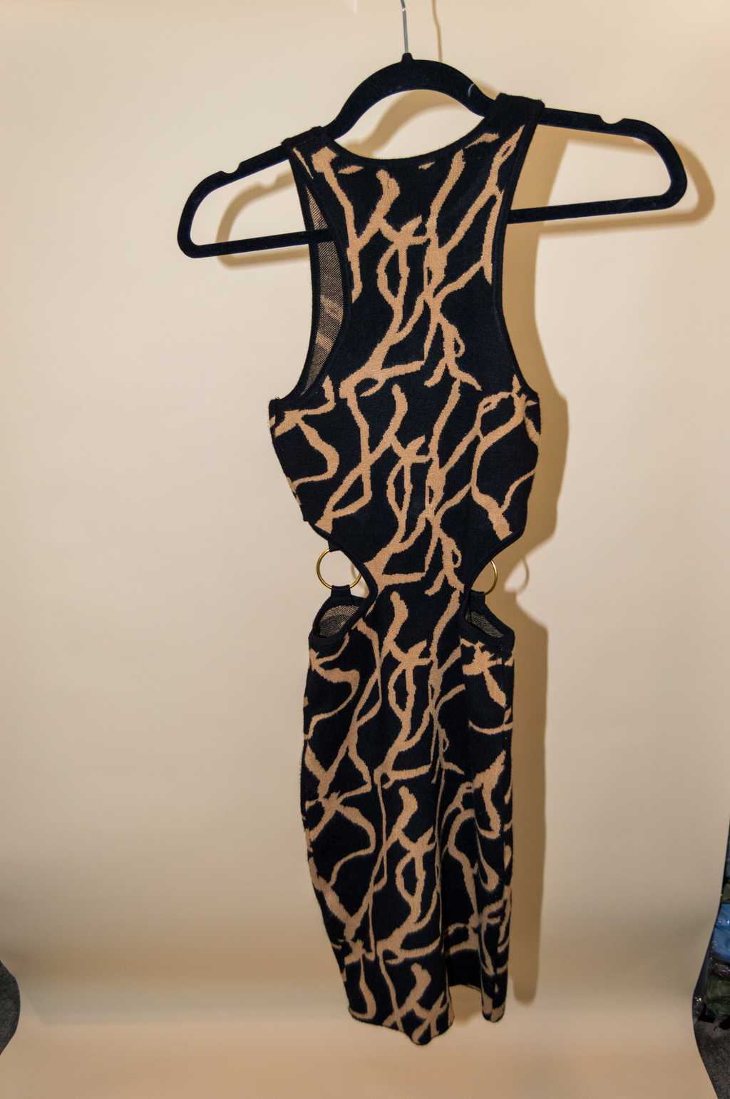 Black and beige patterned jumpsuit on a hanger against a plain background