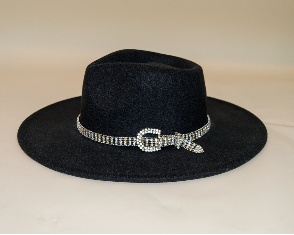 Black hat with a decorative brooch on a beige background