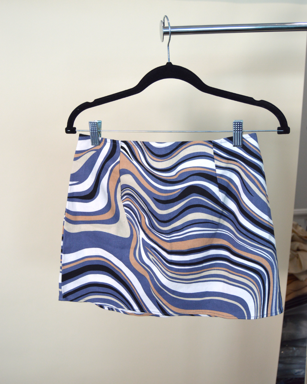 Skirt with wavy pattern on a hanger against a neutral background