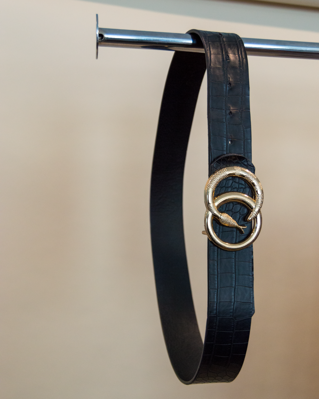 Black belt with a gold buckle on a beige background