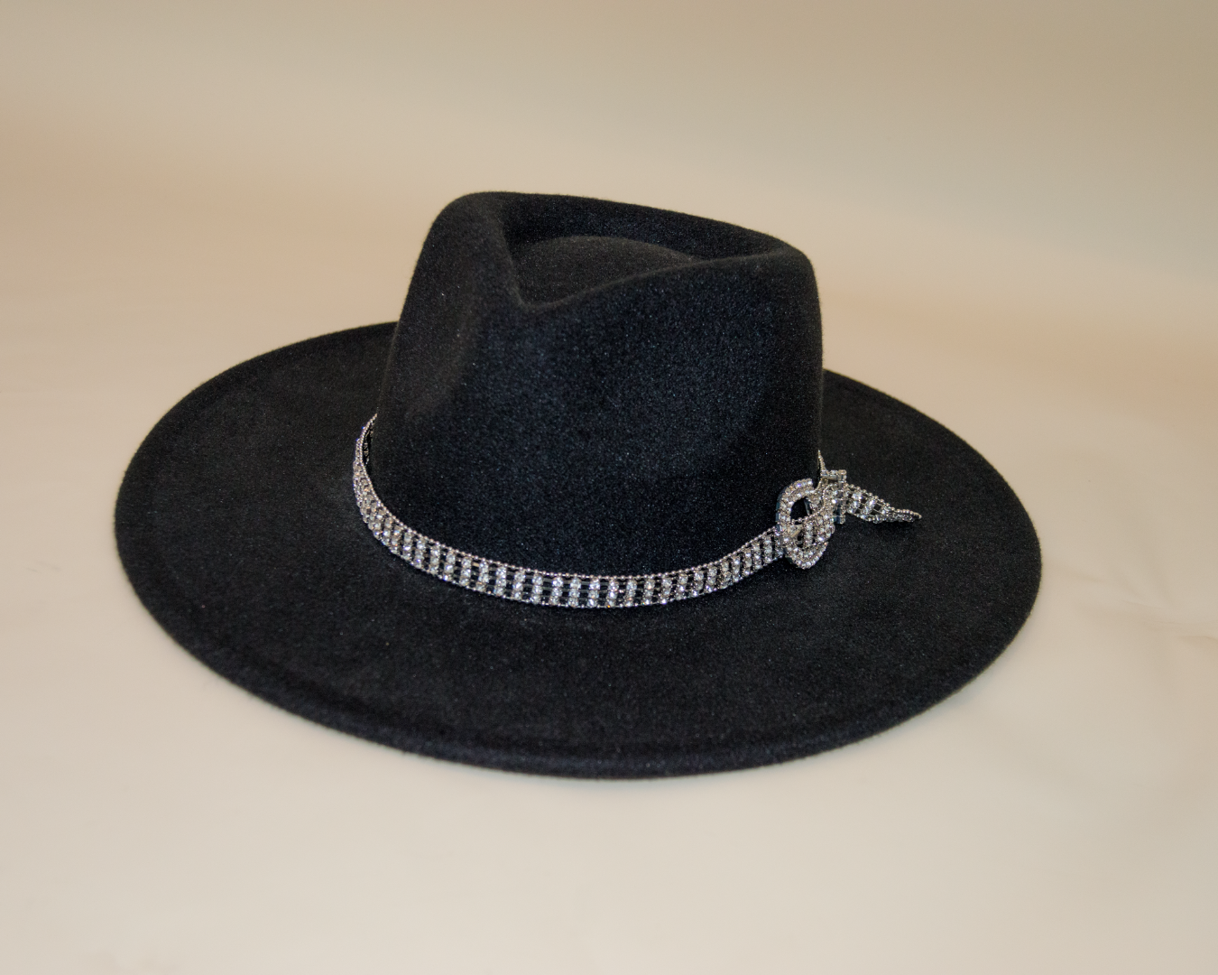 Black hat with a decorative band on a beige background