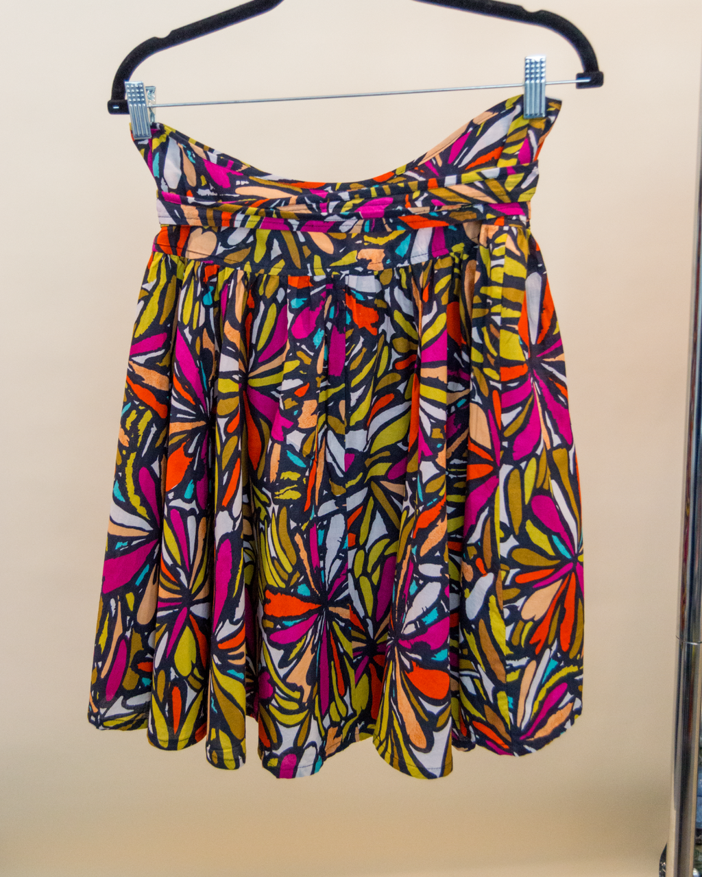Colorful patterned dress on a hanger against a plain background