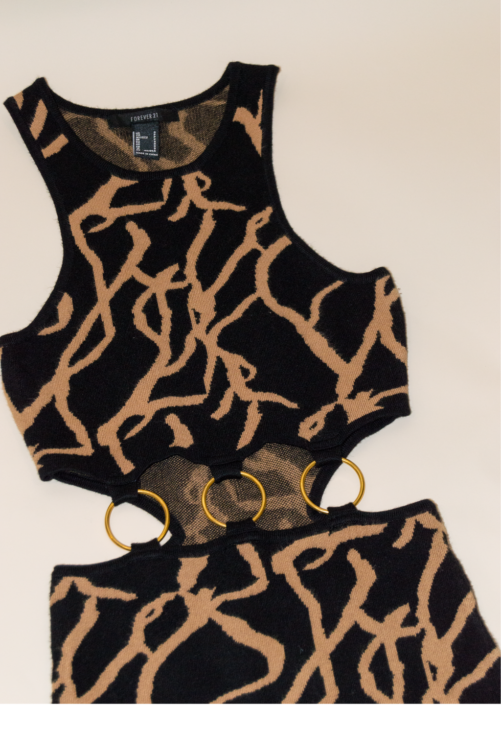Black and gold patterned top with matching shorts on a beige background