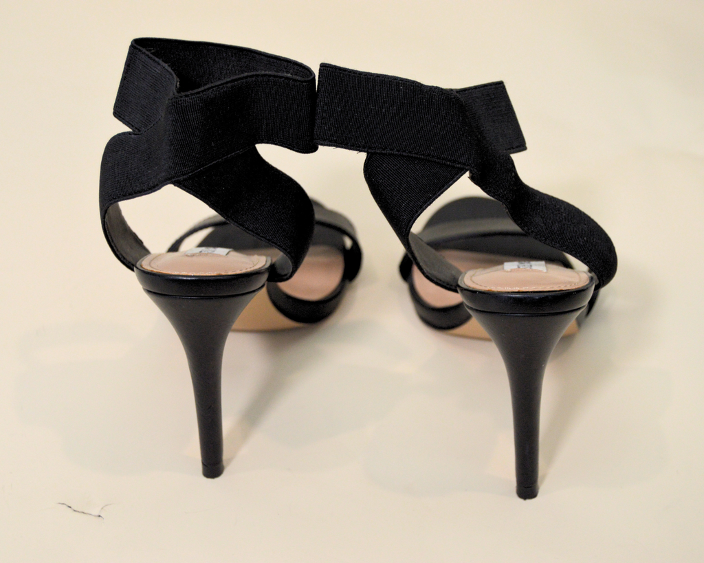Black high-heeled shoes with bow details on a light background