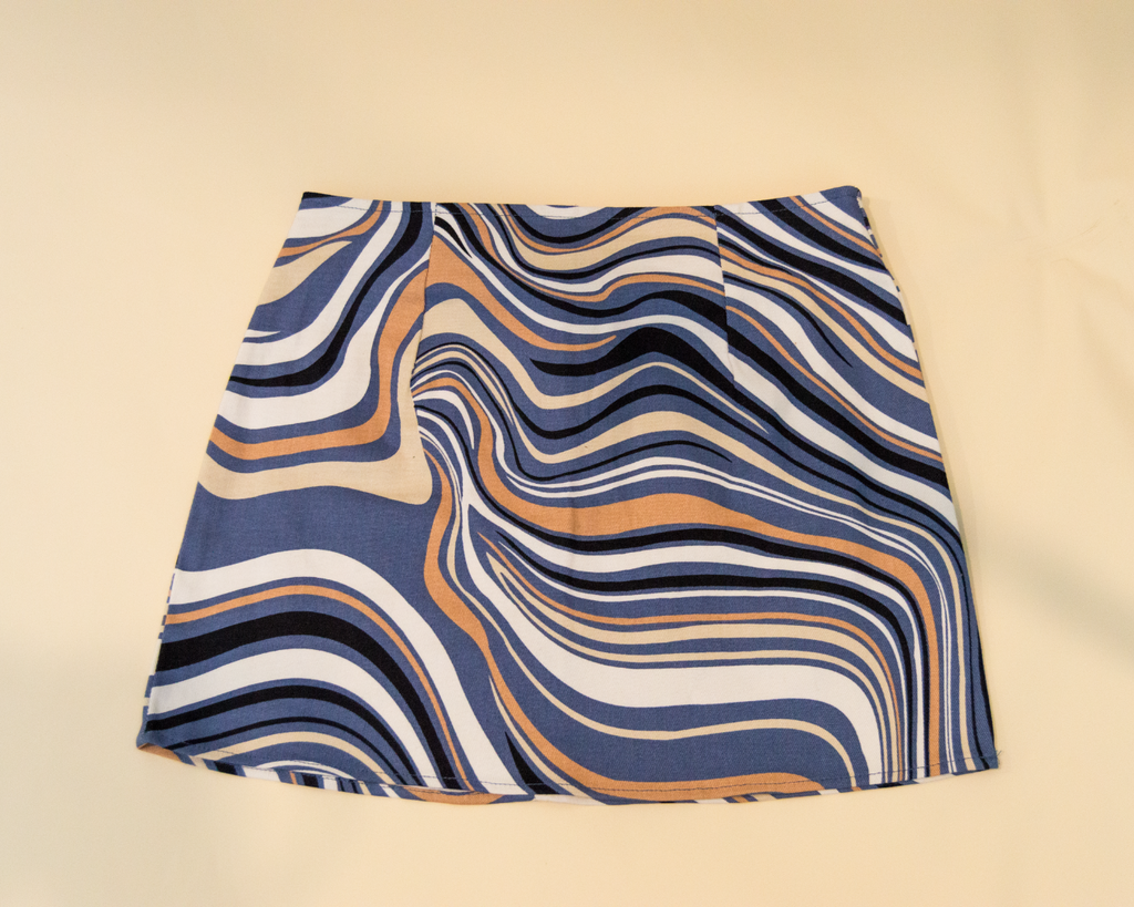 Fabric swatch with wavy blue, orange, and white pattern on beige background