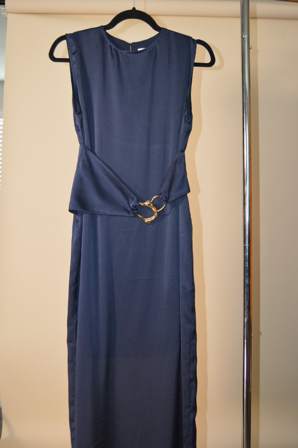 Navy blue dress on a hanger against a beige background