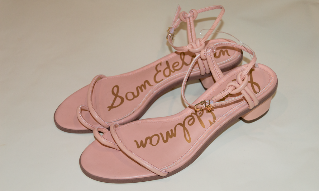 Pink sandals with 'Sam Edelman' branding on a beige background
