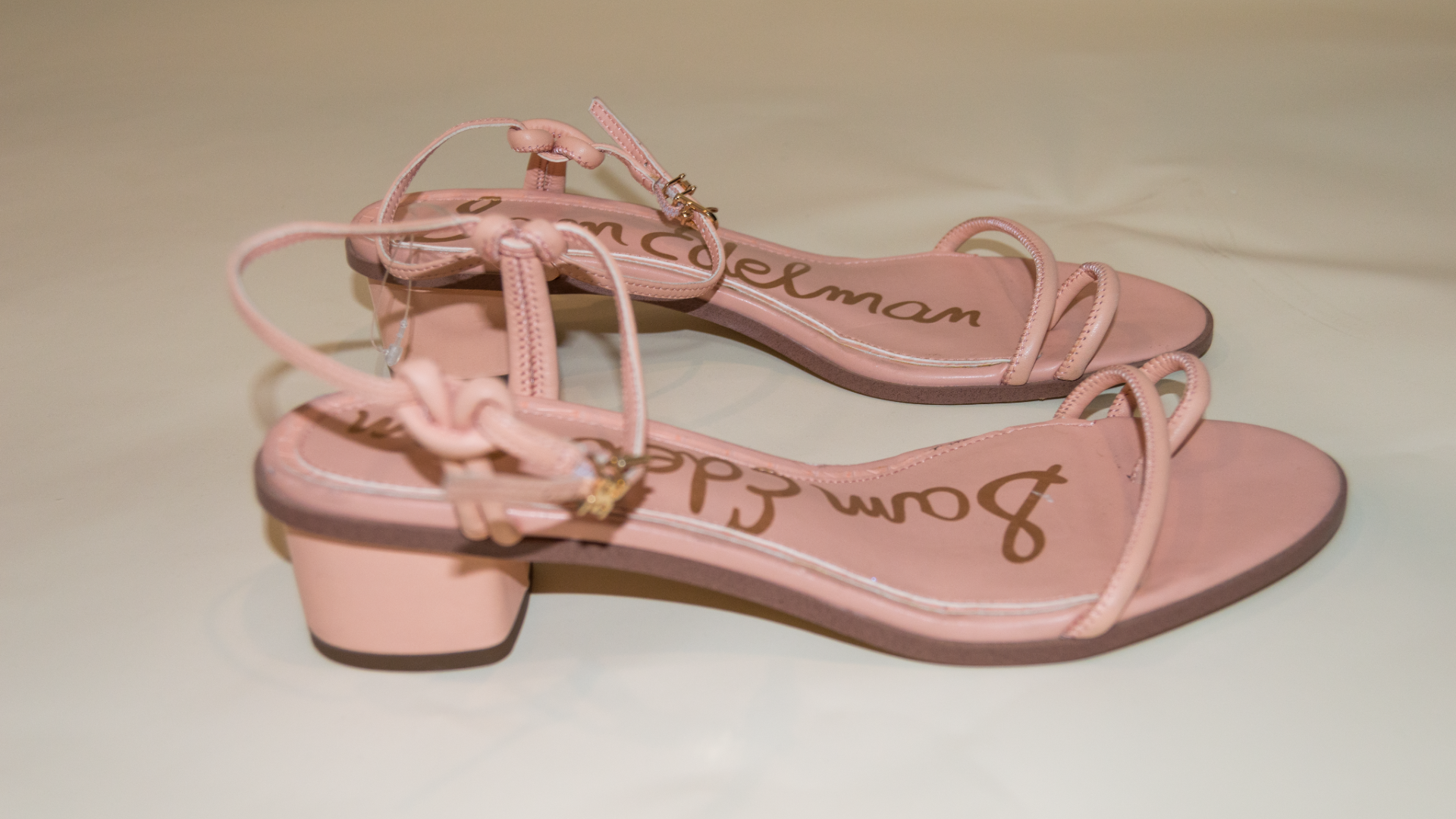 Pair of pink sandals with 'Sam Edelman' branding on a beige background