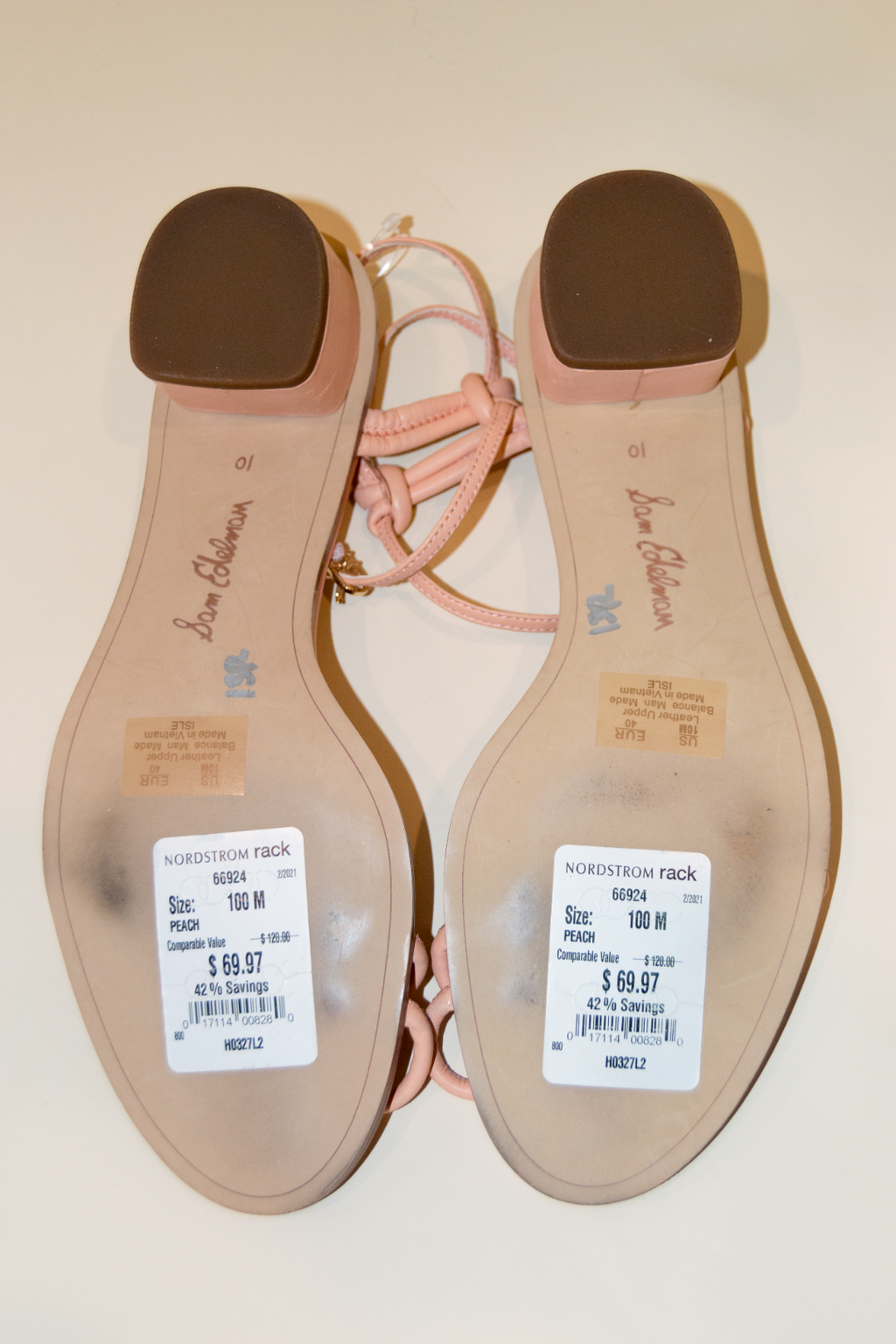 Back view of a sandal with visible brand name and price tag on a plain background