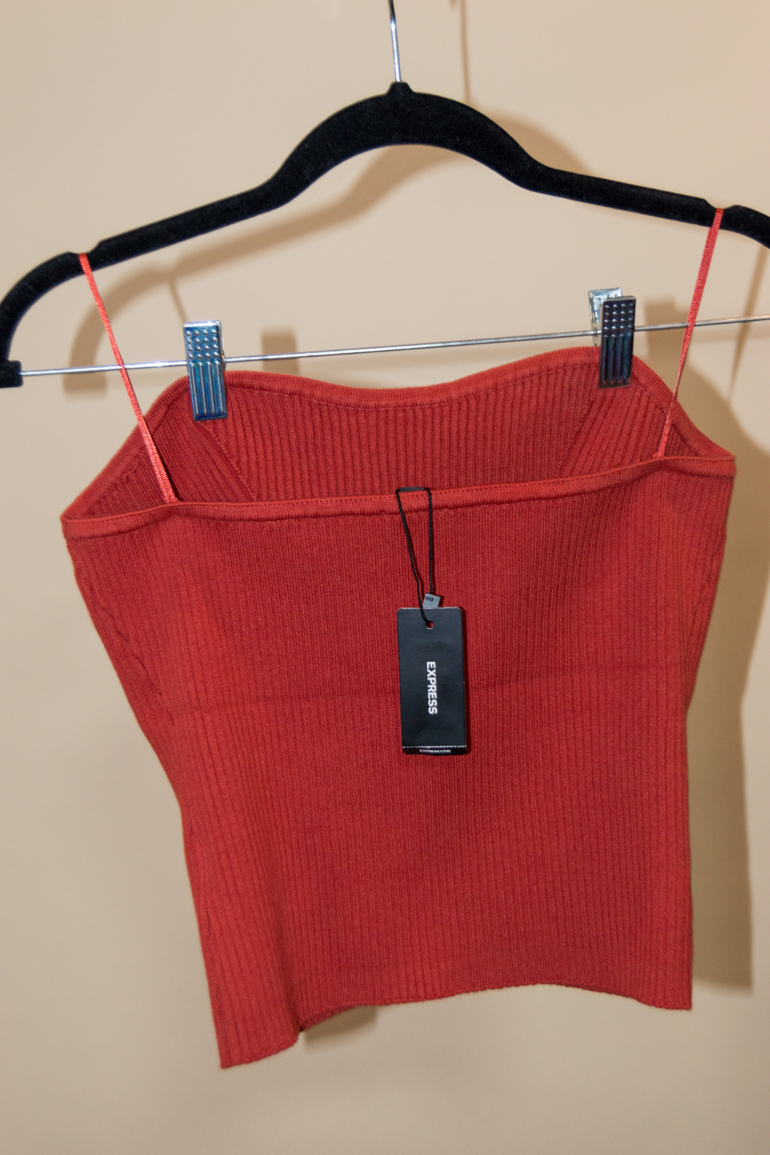 Red crop top with a tag on a hanger against a beige background