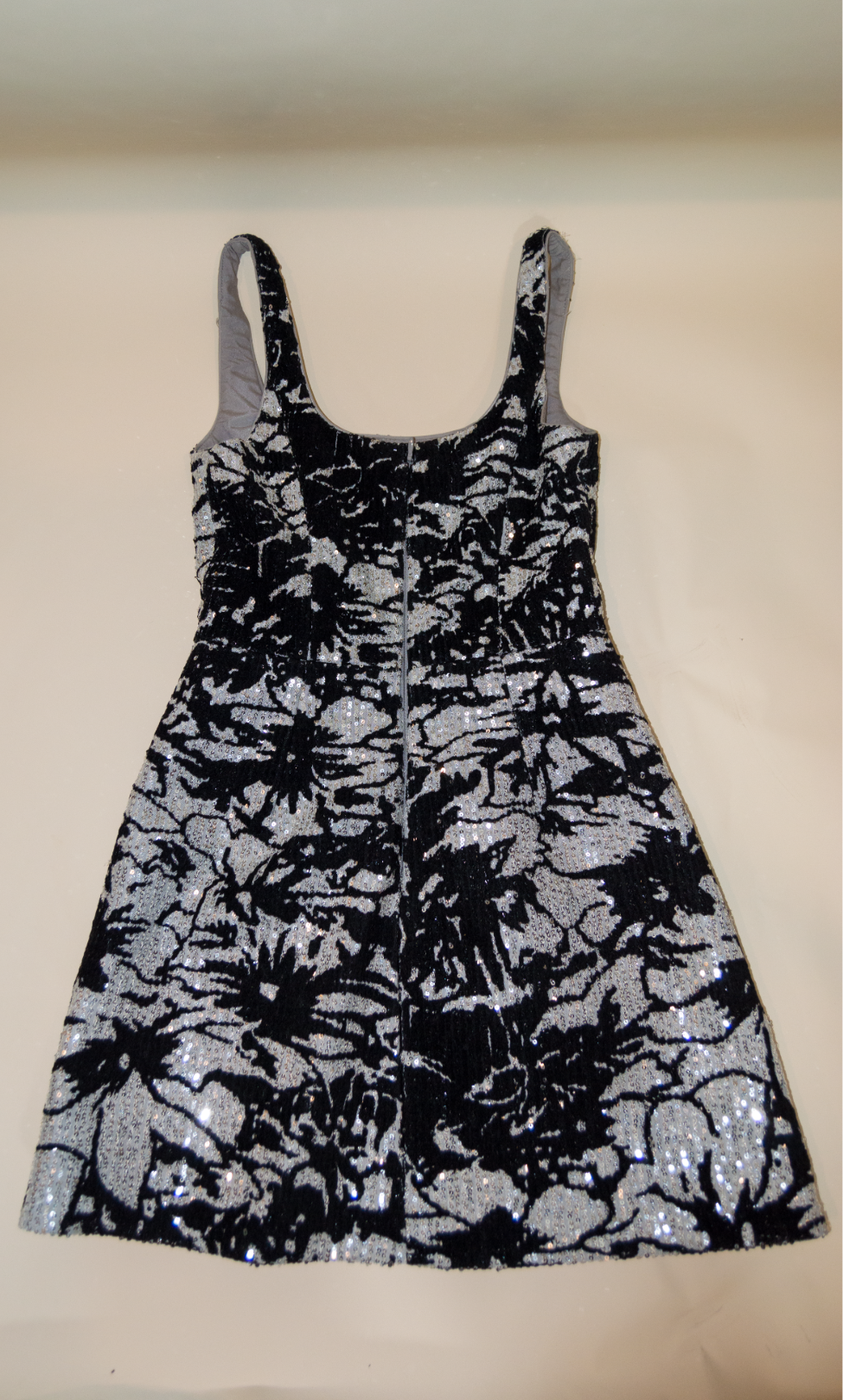 Black floral dress with silver sequins on a beige background