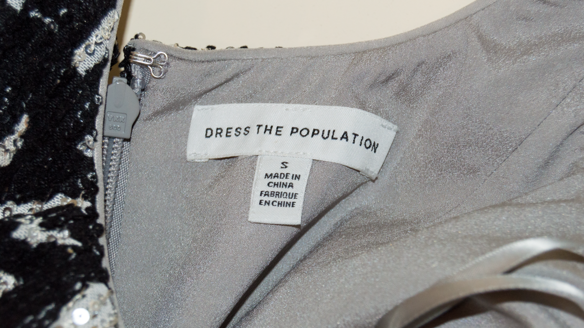 Gray dress with 'Dress the Population' label on a textured background