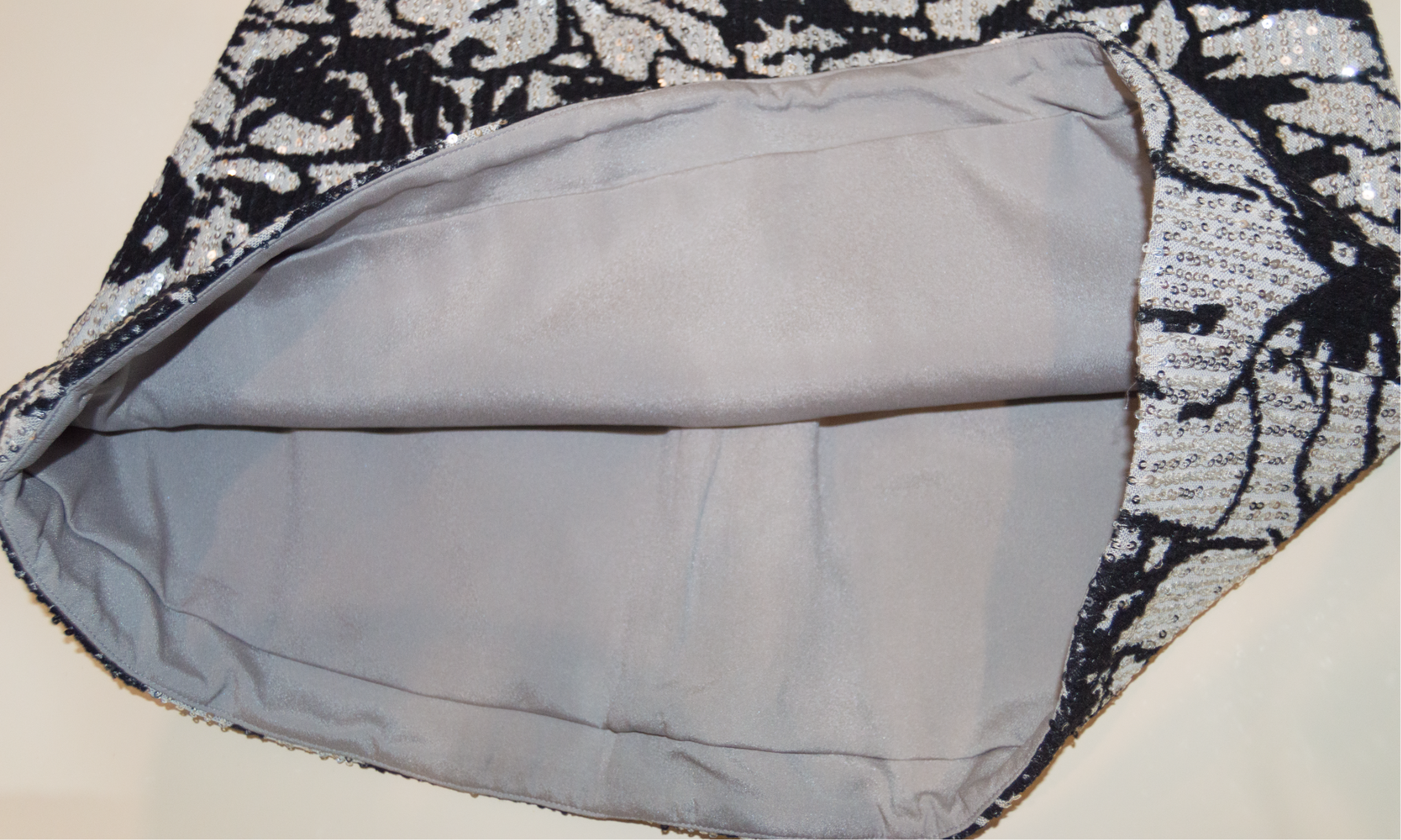 Close-up of a gray fabric with a black and white patterned border on a beige background